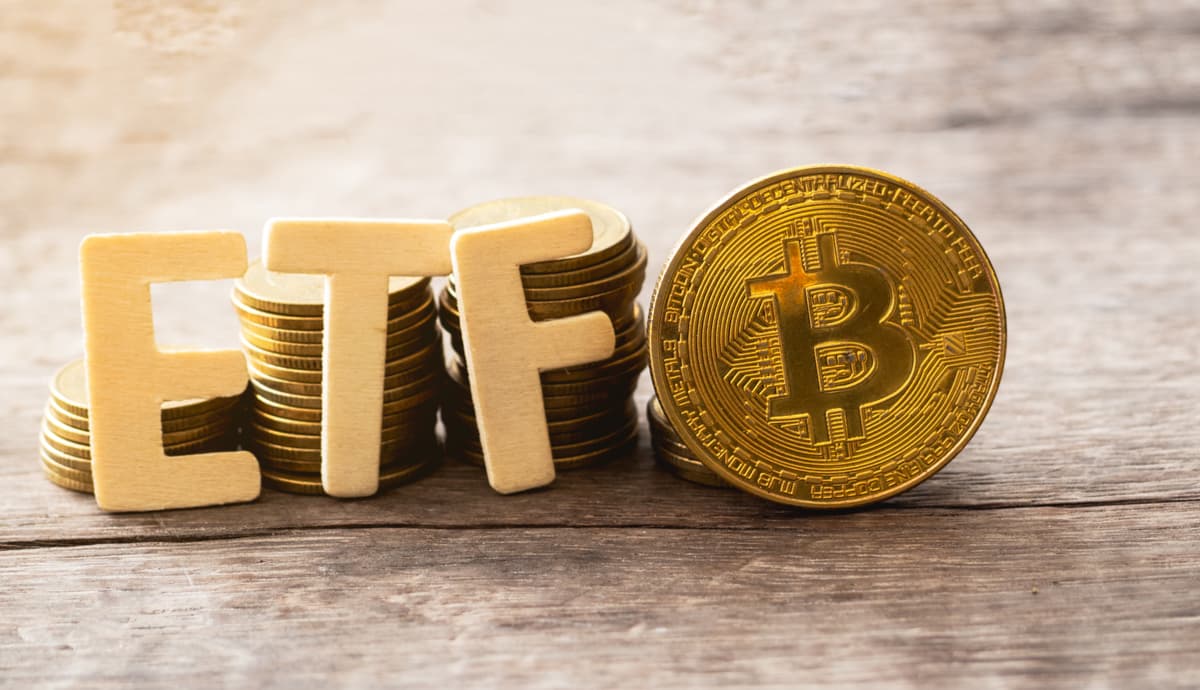 Letras que formam a sigla ETF próximas a uma moeda dourada de Bitcoin (BTC)