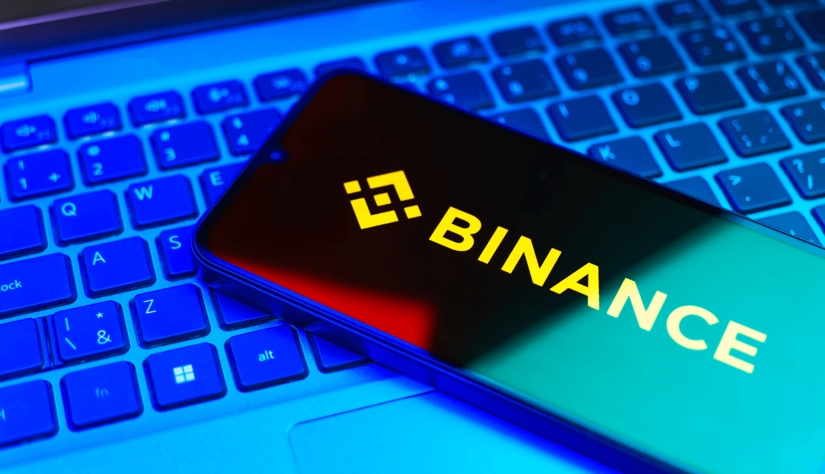 logo da binance em celular em cima de teclado de computador