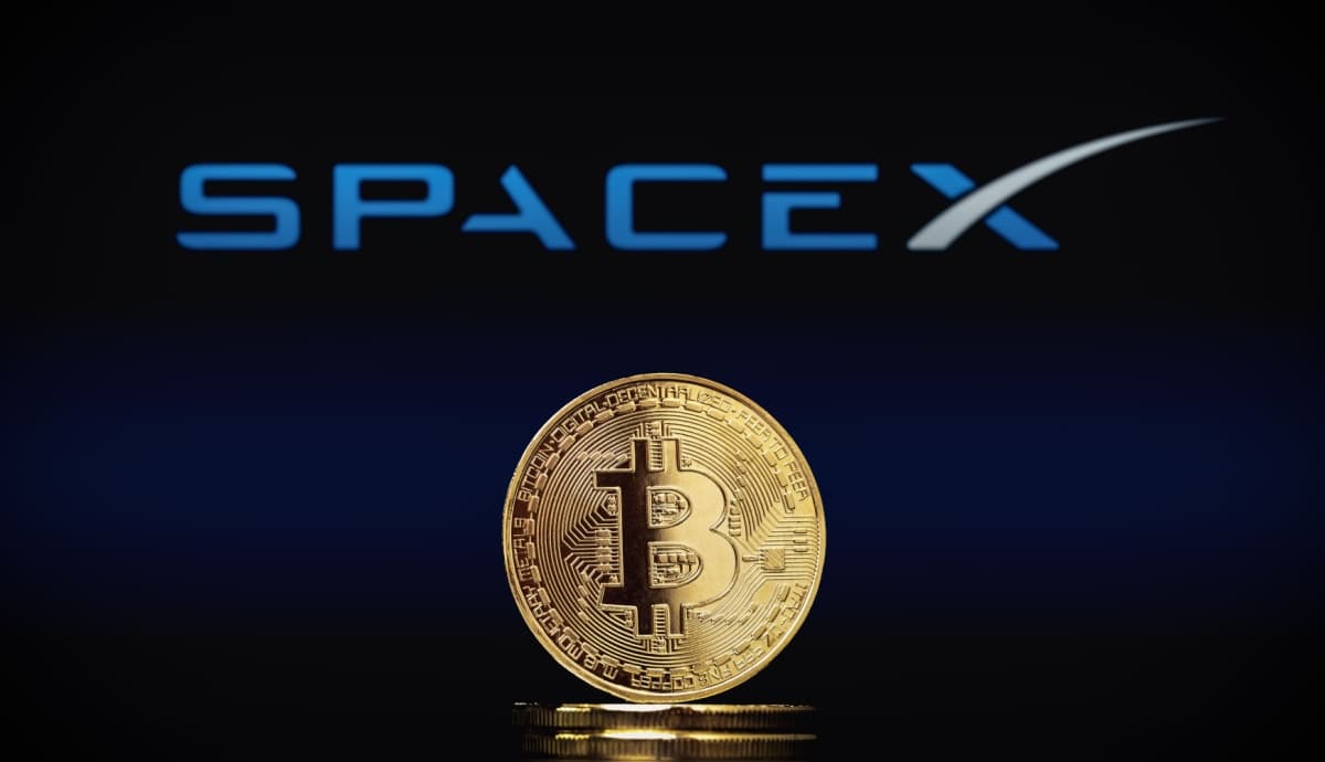 Moeda de Bitcoin à frente de logo da SpaceX